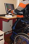 Ein Junge im Rollstuhl trainiert am PC mit Hilfe eines speziellen Joysticks.