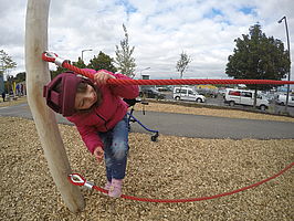 Ein Mädchen steht auf einem Seil auf dem Spielplatz des Außengeländes der Tagesstätte
